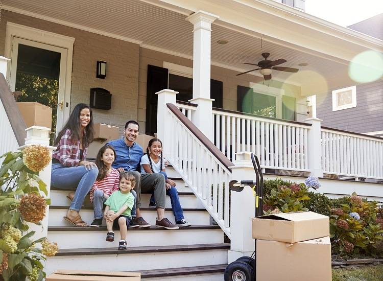 A family sitting on the steps of their new home during move in day
