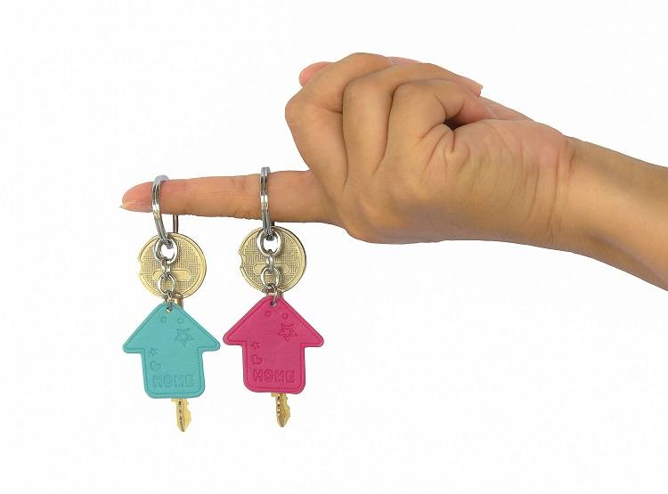 A finger holds two sets of house keys on it