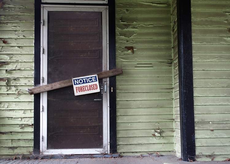 A decrepit house door with a foreclosed sign on it