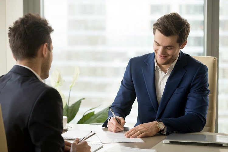 Two smiling businessmen sign contracts