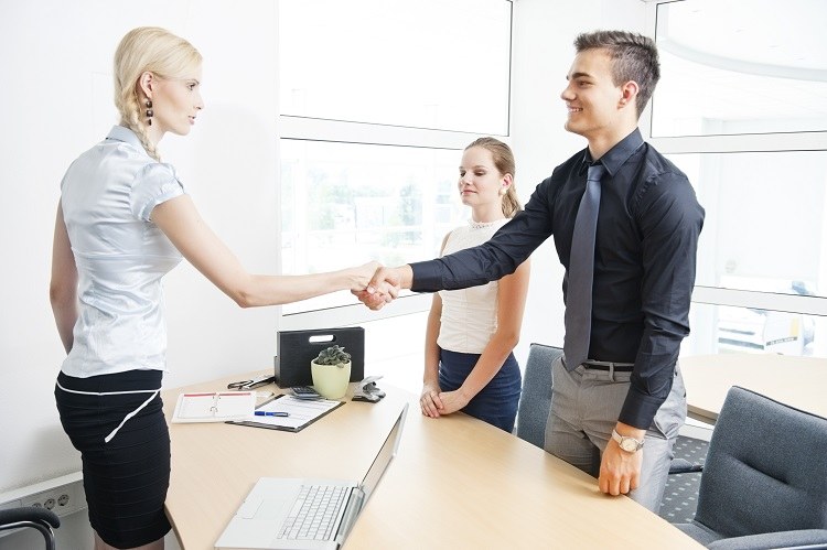 A young couple shakes hands with their mortgage broker